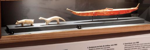 A model boat and a carved bone animal sit in a display case.