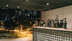 Exterior shot of a group of people on a balcony with a large roof overhang.
