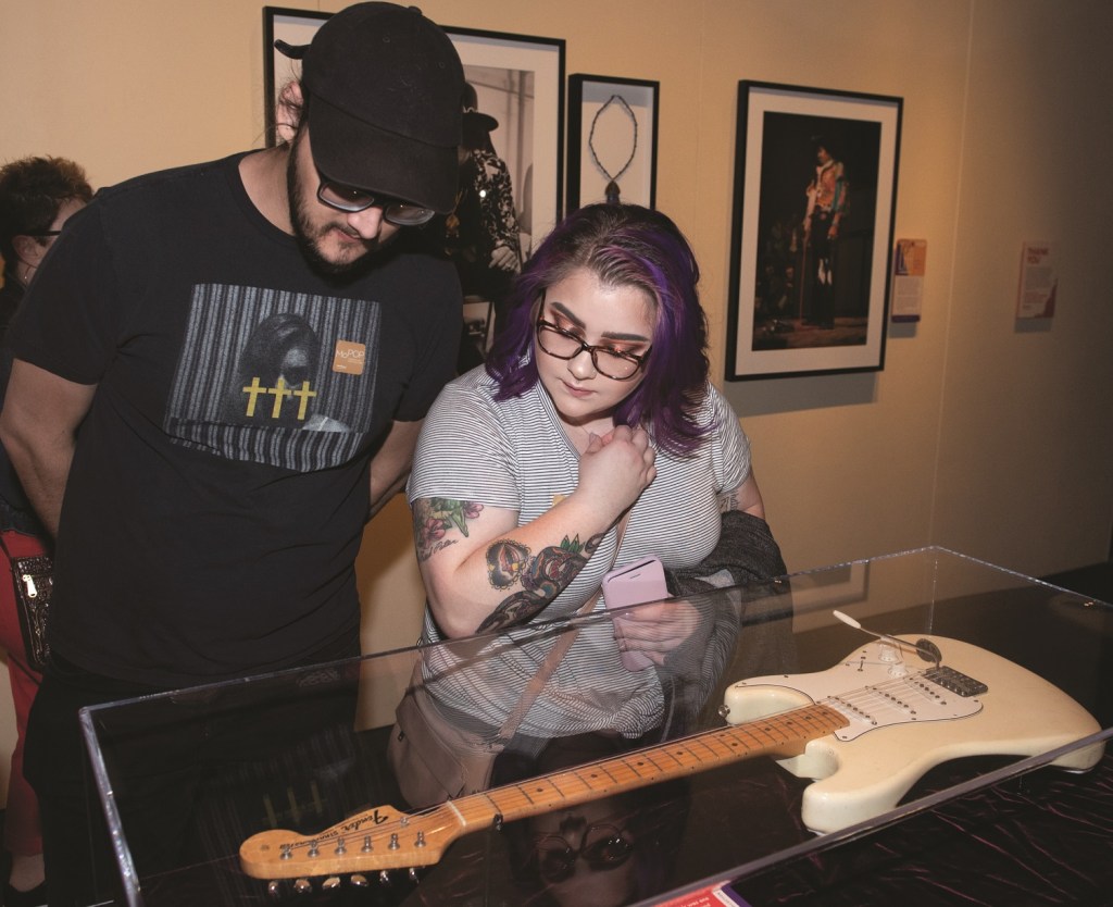 A man and a woman examine a white guitar in a case.
