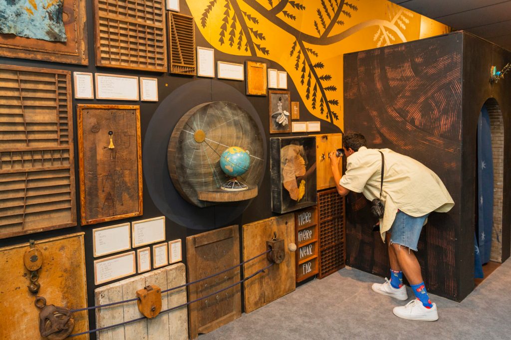 A visitor peering into a peephole on an interactive art installation