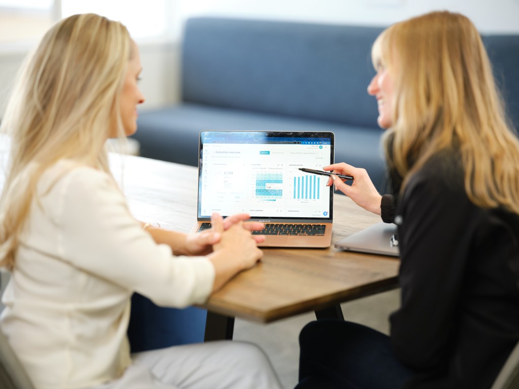 Two people looking at charts on a laptop