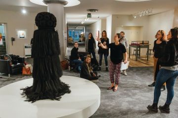 A group of students look at a dress on display in the exhibition. 