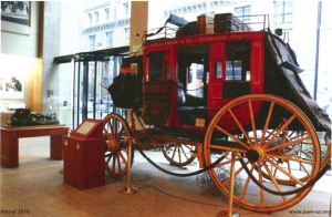 View of a red horse drawn carriage on display in a lobby. 