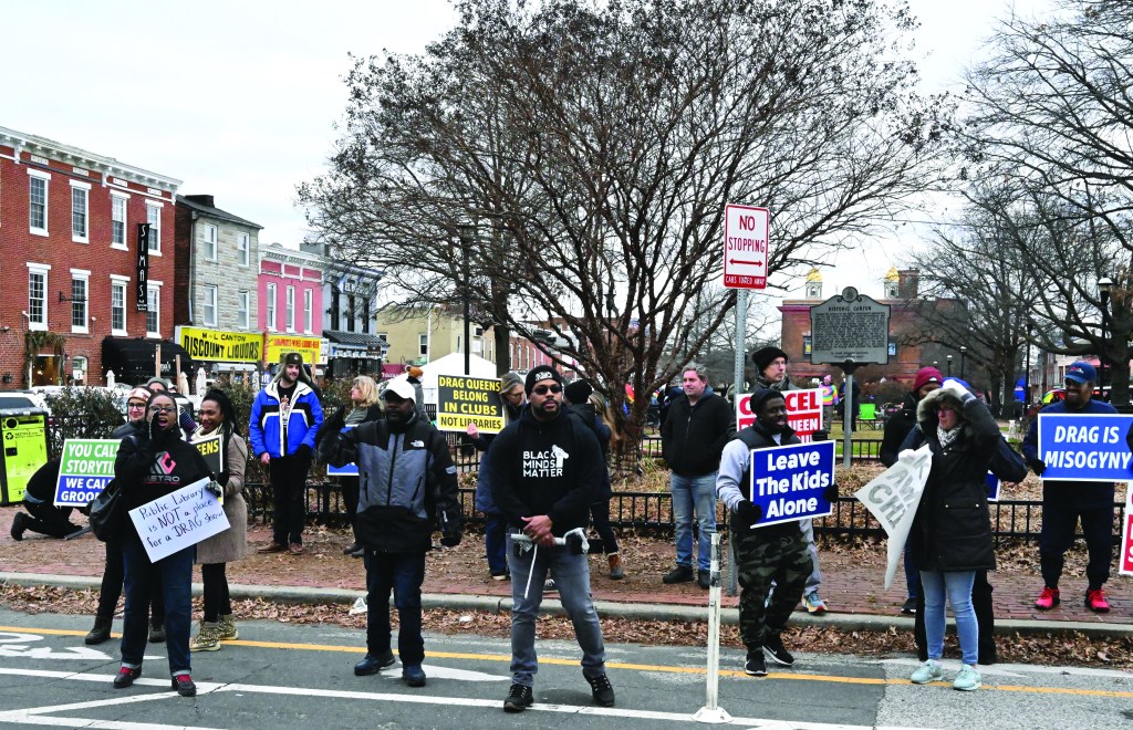 A group of demonstrators congregate on a street with several signs. 