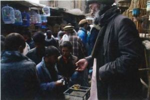 A crowded street with stalls on either side with lots of people milling about. 