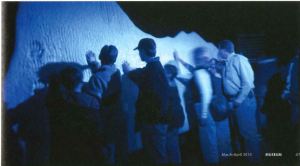 A group of people touch a fake iceberg. 