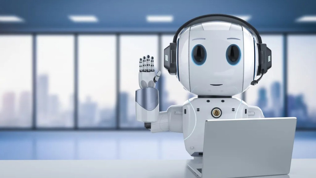 A robot sitting behind a laptop and waving