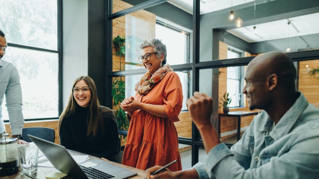 A group of people smiling around a table at an office