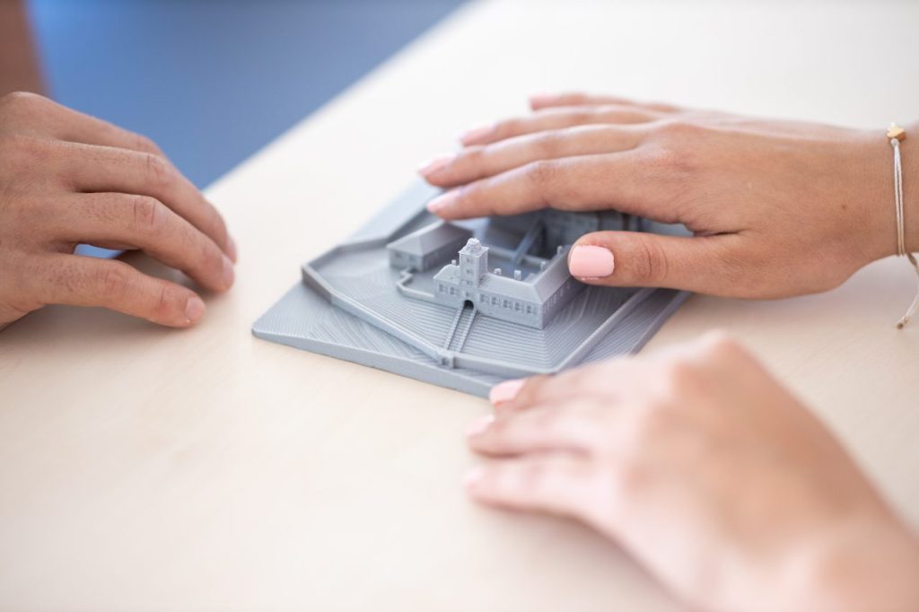 A pair of hands exploring a tactile model of a town