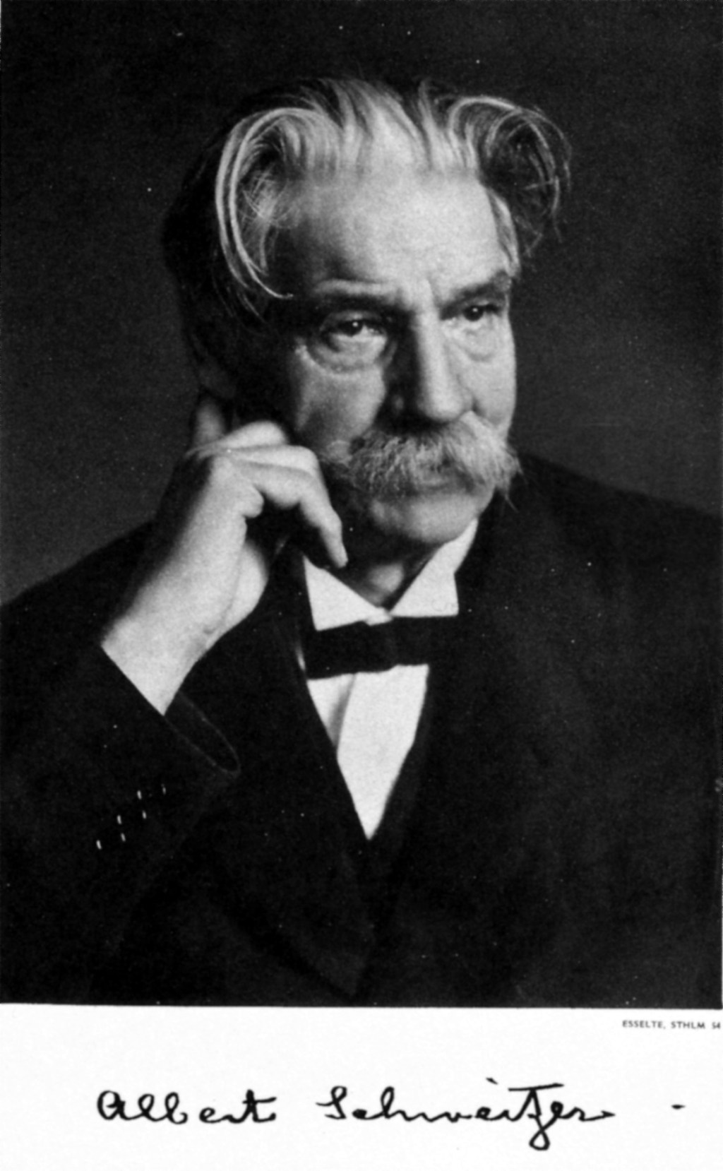Black-and-white portrait photograph of a man in a tuxedo, with his signature underneath.