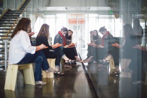 Four women sit in front of a reflecting wall.