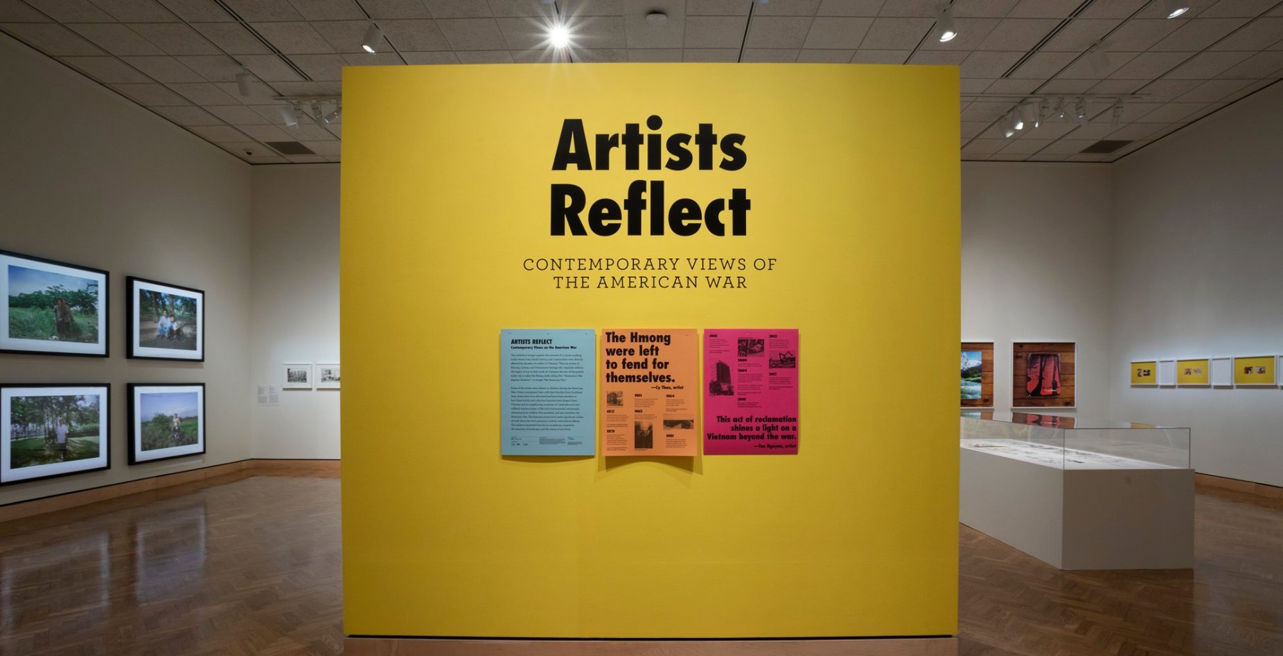 A title wall for the "Artists Reflect: Contemporary Views of the American War" exhibition, with a timeline and quotes reading "The Hmong were left to fend for themselves" and "This act of reclamation shines a light on a Vietnam beyond the war."