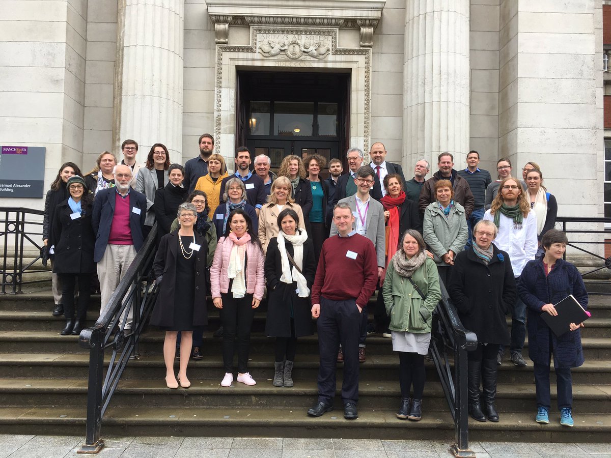 A group of about 50 people standing on the steps outside a classical looking building.