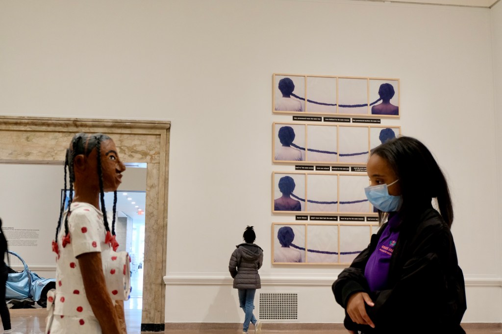 A masked person looking at a human-like sculpture