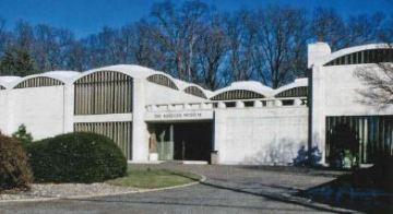 A large white building sits at the end of a circle drive.