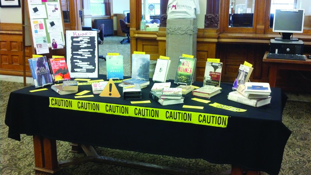 A group of banned boxes on a table covered in a black tablecloth with caution tape taped to the front.