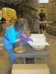 A grey haired woman examines a basket on a folding table with foam inside it. 