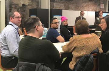 Eight members of CAMP are shown seated around a conference table attending a breakout session at a CAMP meeting where they discussed challenges with LGBTQ inclusion at museums and potential solutions to them.