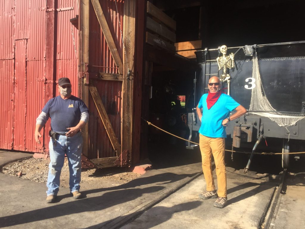 Two people stand in front of a train roped off inside a building