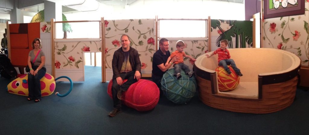 A family sit on oversized extra large skeins of yarn.