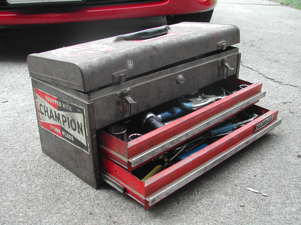 An old toolbox with a "champion" sticker on the side and two drawers partially open