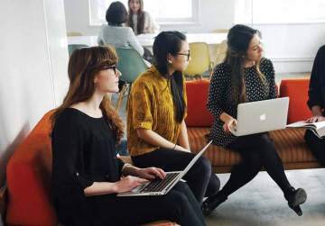 A group of workers sit on couches with laptops