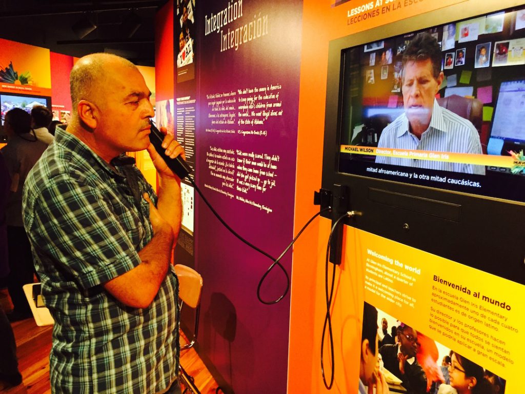 A man holds a phone to his ear as he listens to a video in an exhibition