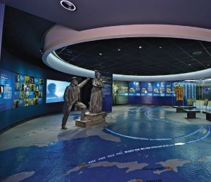 Exhibition with grey statues and a world image on the floor. 