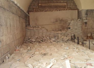 View of the mosaics with sand bag and dirt in front. 