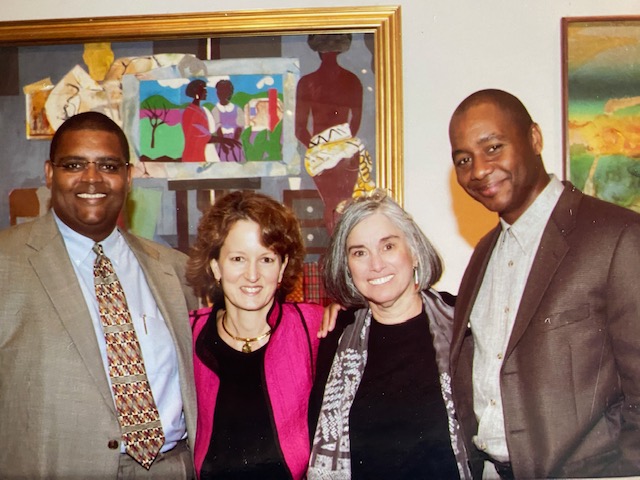 Four people standing in front of two paintings