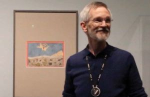 Jeff Byers standing in front of a framed sketch on paper. 
