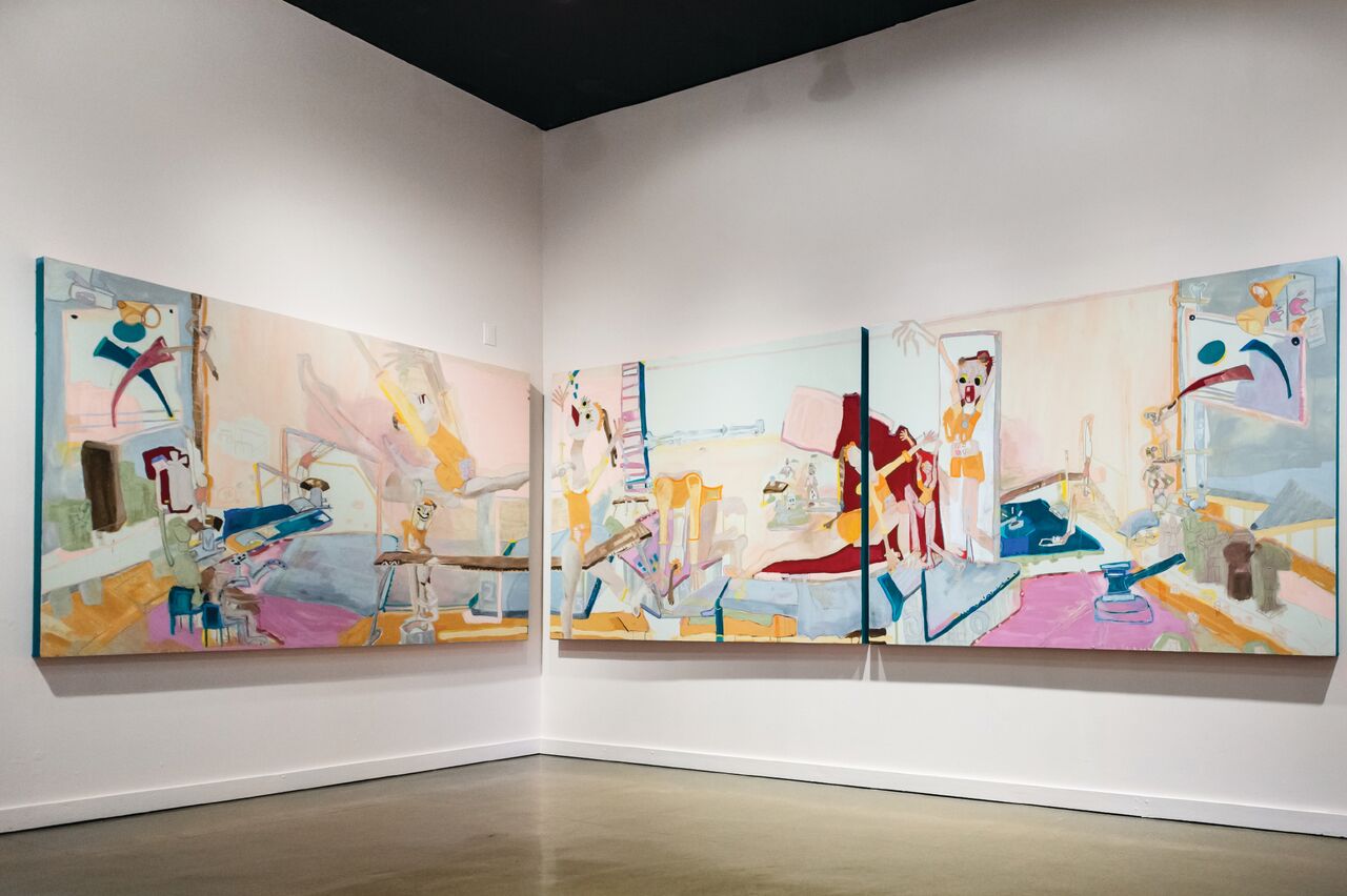 Paintings hanging on a white wall together in a corner. 
