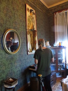 A woman looks toward a wall in a historic house with an anatomical drawing displayed.