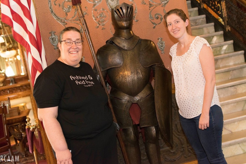 Two women pose with a knight in shining armor. 