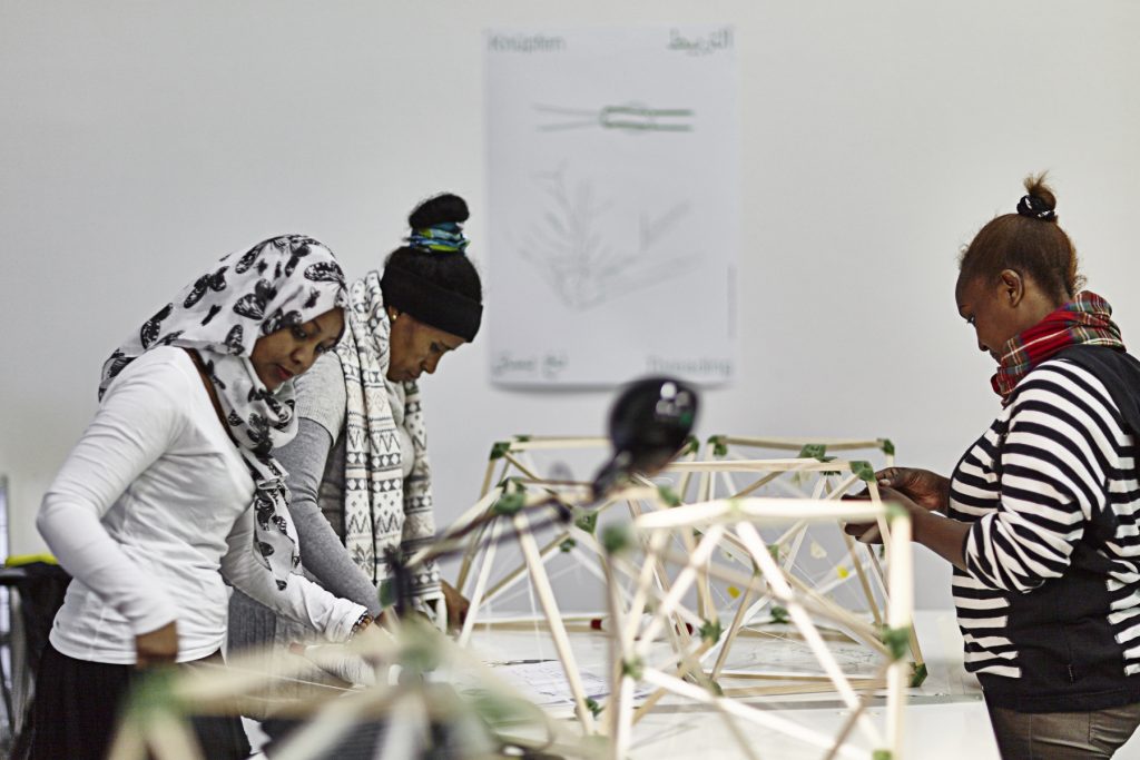 A couple of women are looking down at an exhibit on a table.