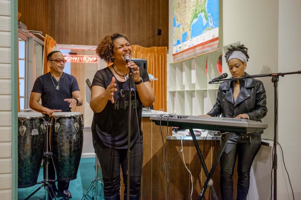 A group of musicians play and sing in the Motel Sessions exhibition. 