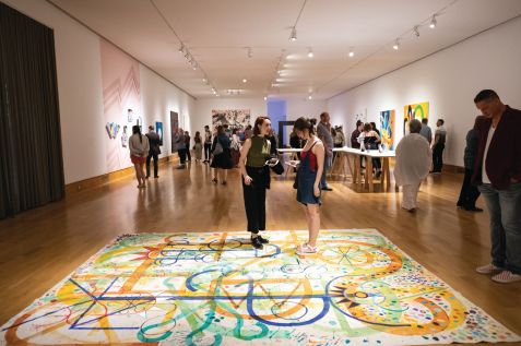 Two people stand on a floor with lots of swirly colored lines.