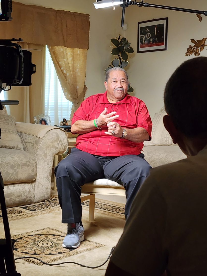 An interview subject seated in front of a camera crew