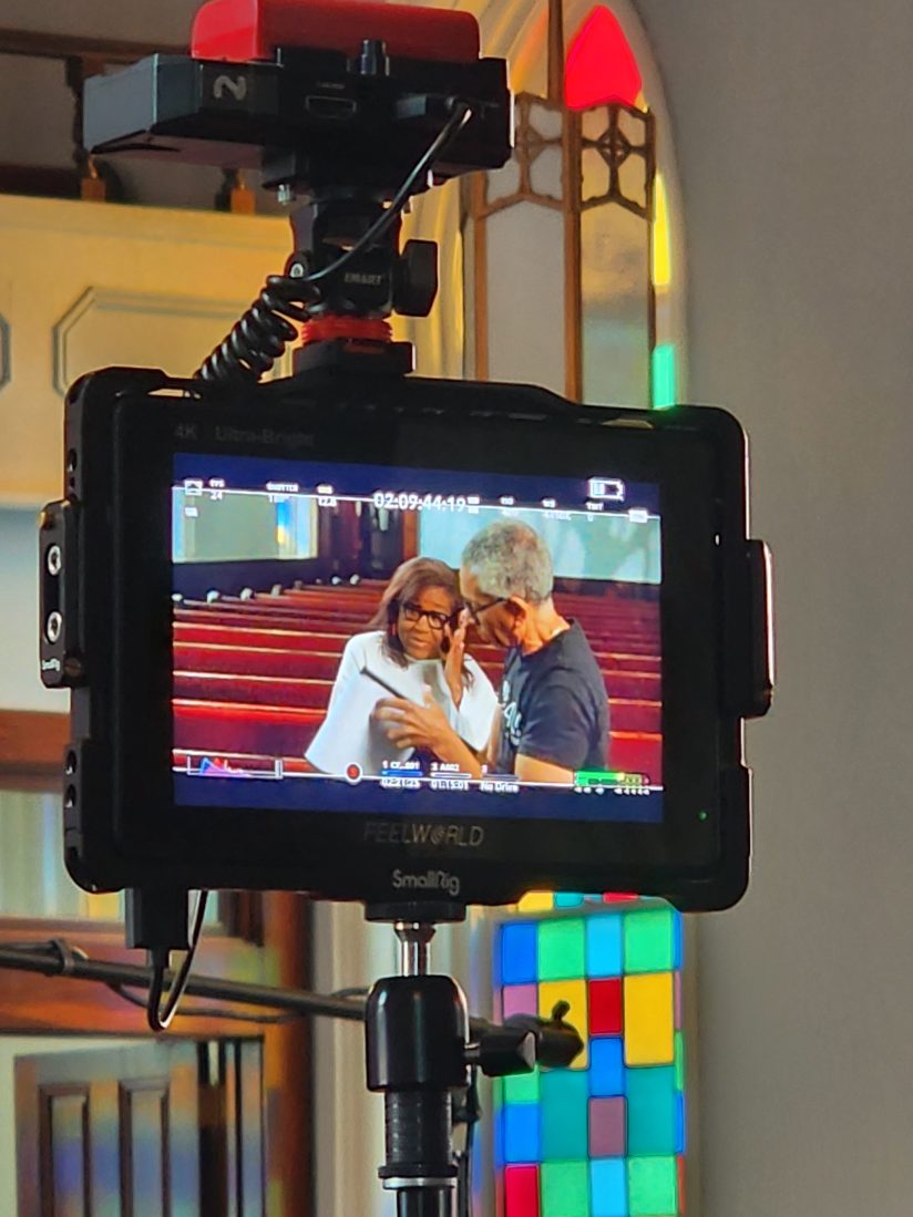 A camera monitor showing an interviewer speaking to a subject