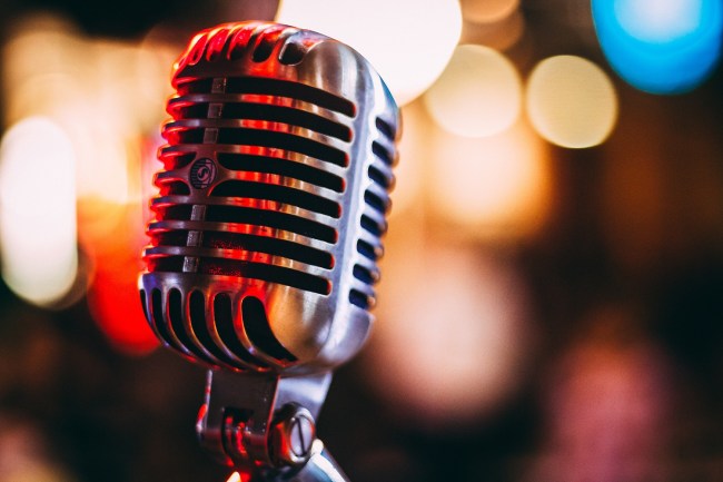 Silver old style microphone with blurred out lights in the background.