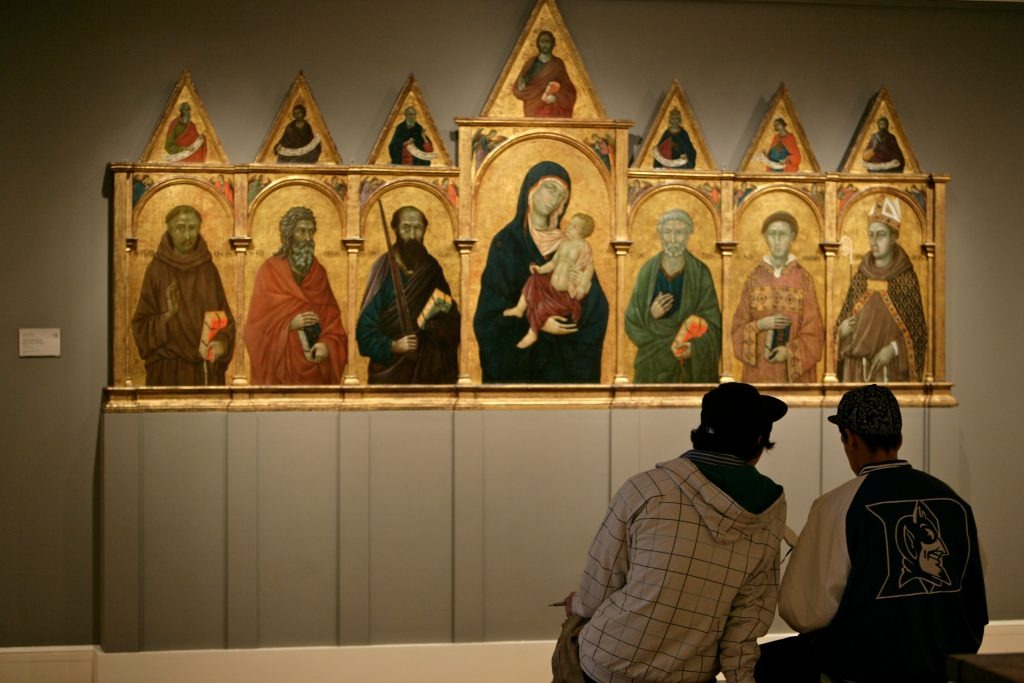 People sitting in front of a gilded altarpiece