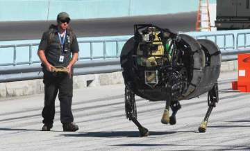 A man controls a large headless robot running down a road