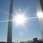 Metal arch in St. Louis, Missouri at dusk with sun shining through.