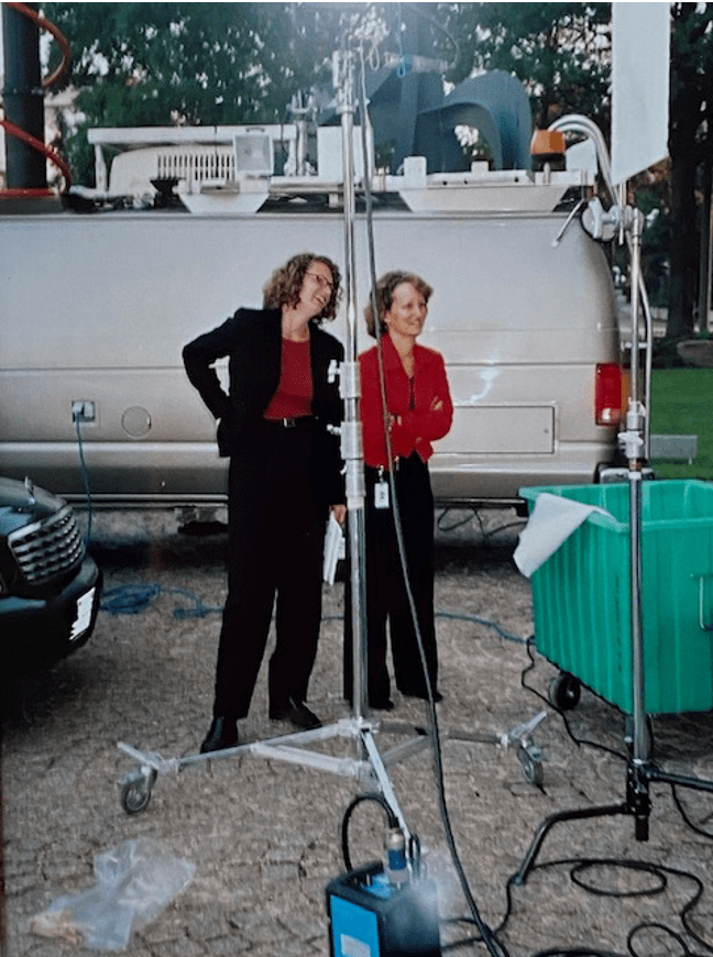 Two people standing next to a van with a camera
