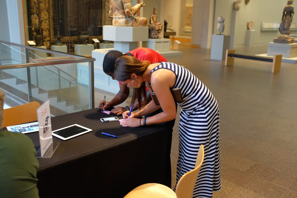 A couple lean over a table writing on Post-It notes