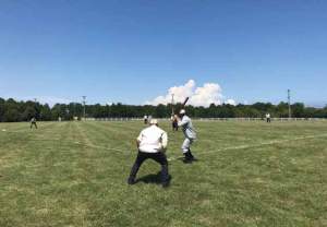 Two men stand on a baseball field one pitching and one catching.