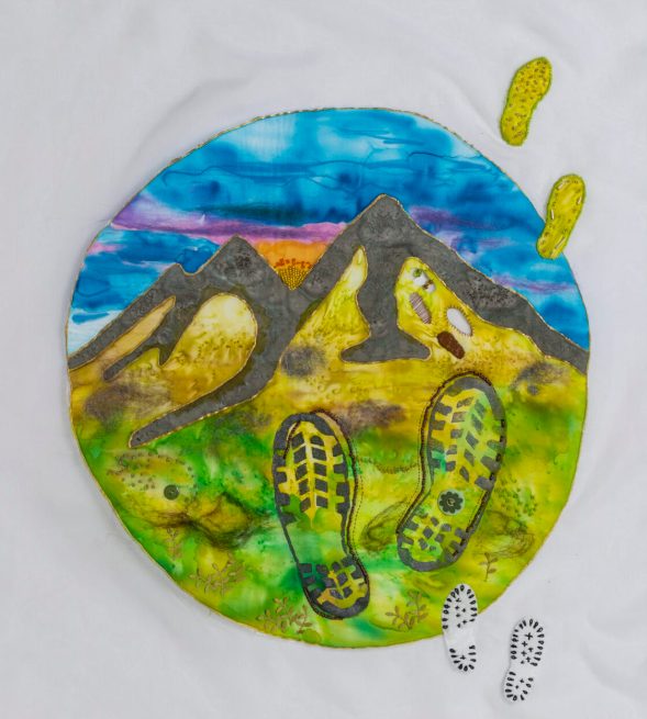 A textile piece depicting a mountain range and boot tracks