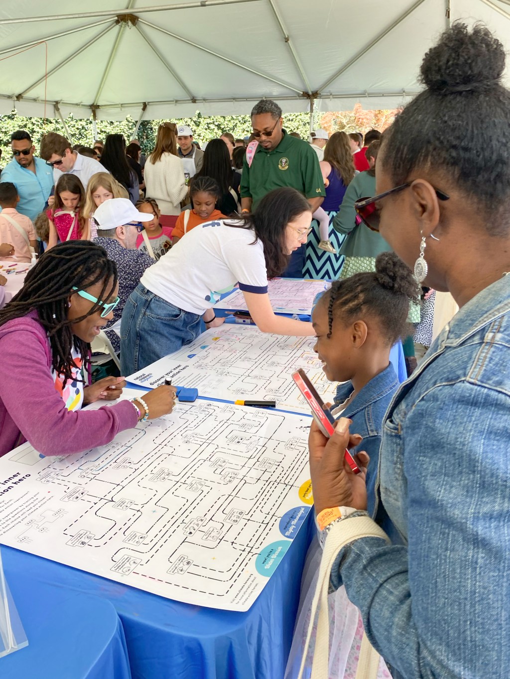 Children and adults completing an interactive exercise on a table at an outdoor event