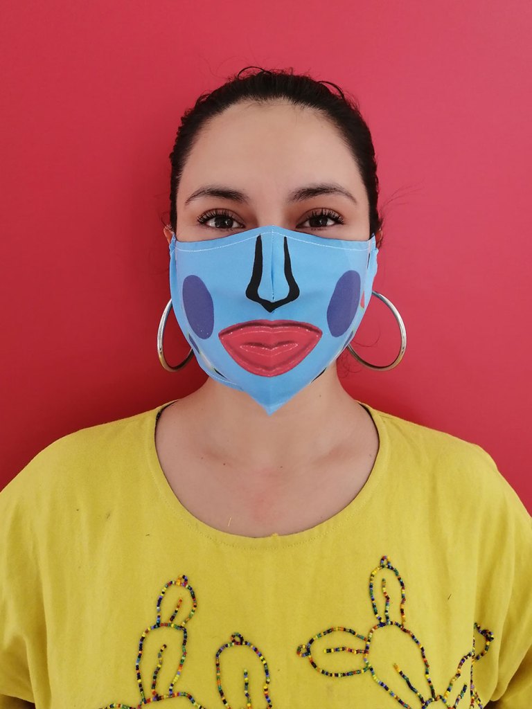 Photo of a person wearing a blue face mask with a stylized nose, lips, and cheeks drawn on it