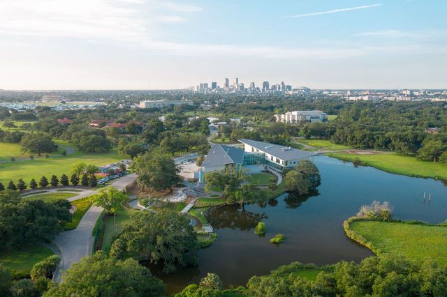 An areal view of the Louisiana Children's Museum with a large curved structure sitting in the middle of a lake area.
